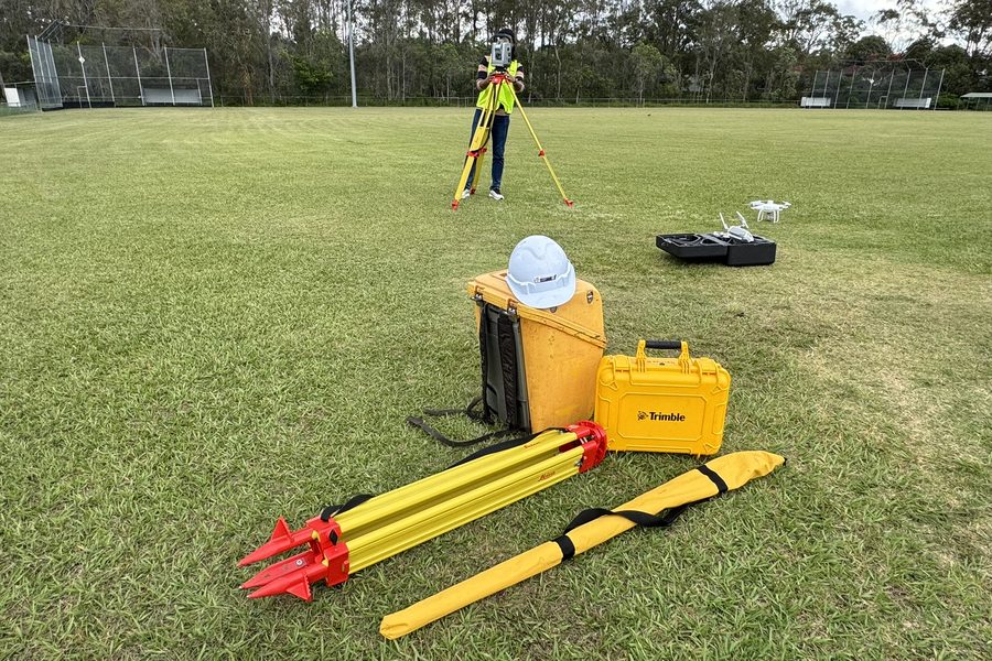 Survey equipment laid out on a field: tripod, ranging poles and equipment cases