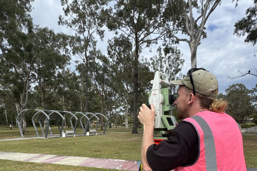 A student setting up a total station on a tripod in a park
