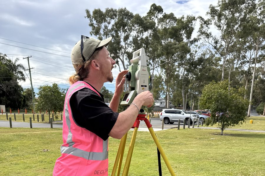 A student setting up a total station during an outdoor practical session
