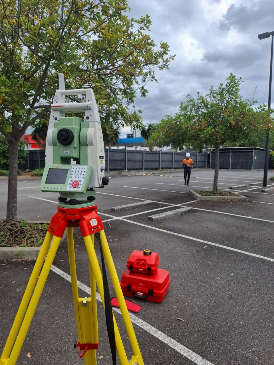 A total station set up on a tripod in a car park