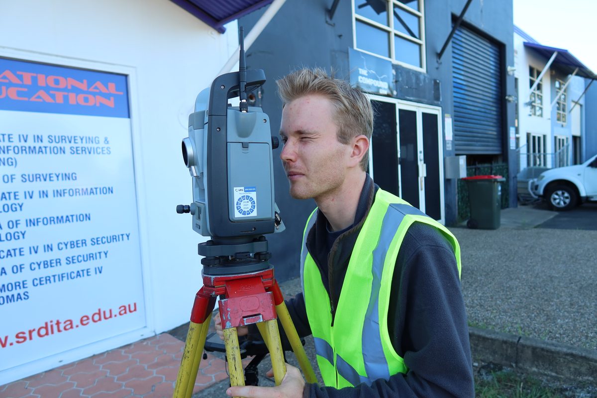 A student using a total station beside the SRDITA building